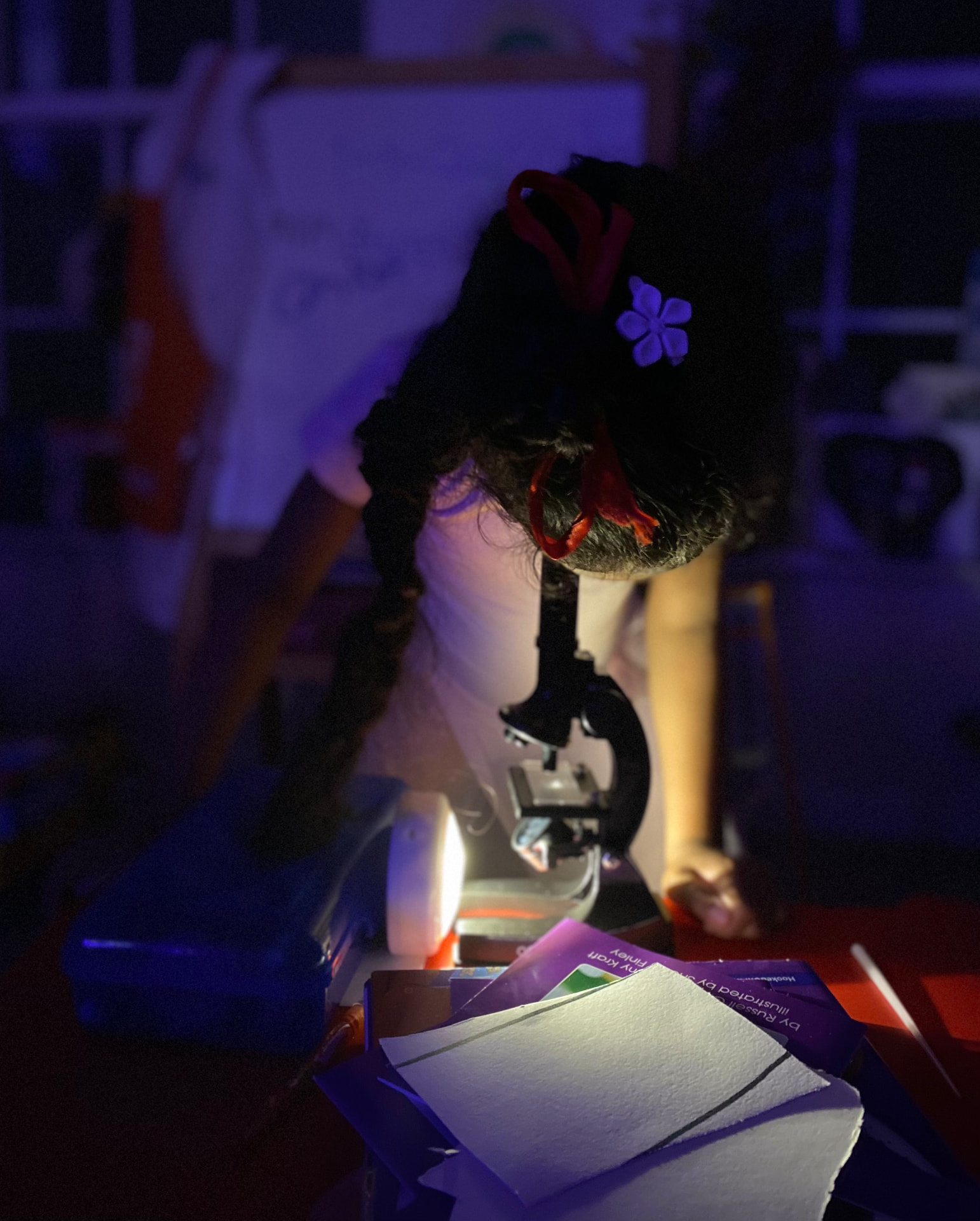 Ishara looking through a microscope under blue light